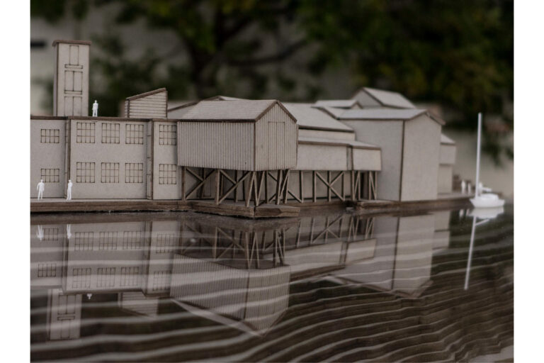 At the edge between the sea and land. Model of original buildings in scale 1:200, seen from the sea.